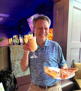 Flipside's food and fun during August, 2026 Members only Activity Event sponsored by Northern Colorado Community A member representative of Northern Colorado Community is enjoying an evening a Flipside with drink and pizza in hand.